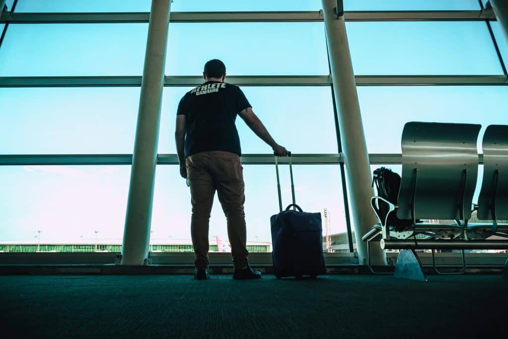 a man standing at airport terminal with hand luggage
