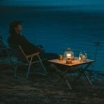 Naturehike Star Jane L01 egg roll table with a lantern beside a lake at dusk